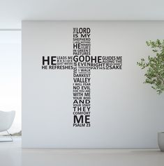 a cross made out of words on a wall in a room with a potted plant