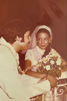 an old photo of a man and woman in wedding attire sitting down with each other