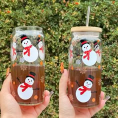 two people holding up glasses with snowmen painted on the glass and one has a straw in it