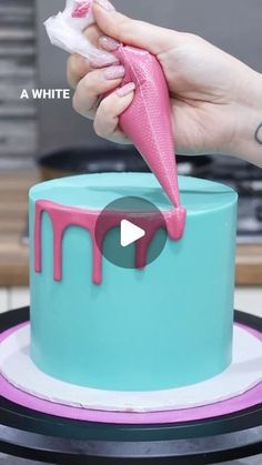 someone is decorating a cake with pink icing