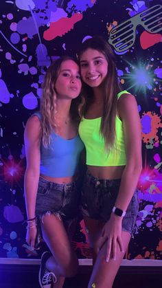 two young women posing for a photo in front of a colorful background