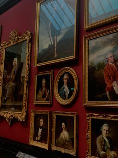 many paintings are hanging on the red wall