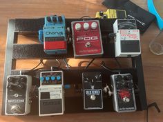 several pedals and other electronic devices sitting on a wooden table next to each other