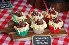 cupcakes with spaghetti and meatballs in them are on a wooden platter