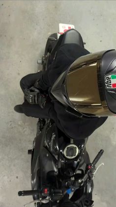 a motorcycle parked in a garage next to a cement floor with the seat up and helmet on it