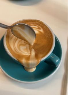 there is a spoon in a cup of coffee on the saucer, with liquid pouring into it