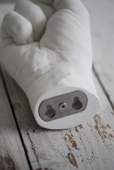 a close up of a white object on a wooden surface with one hand holding the other