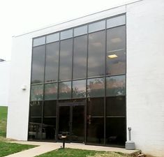 an empty building with large windows on the outside and grass growing in front of it