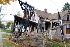 a wooden boat with two men on it in front of a house decorated for halloween