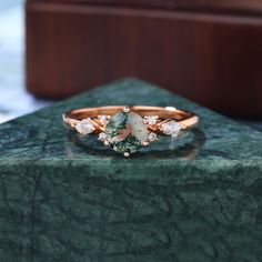 a close up of a ring on top of a green marble table with a wooden box in the background