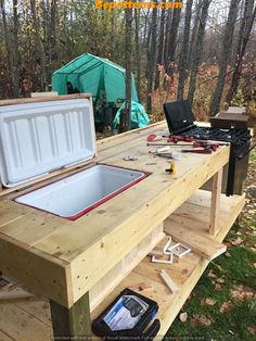 an outdoor kitchen made out of wood with tools on the table and in the background