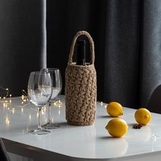 a table with two wine glasses and three lemons on it next to a bottle of wine