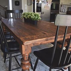 a kitchen table with chairs and a potted plant sitting on top of the table