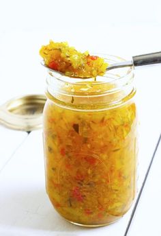 a jar filled with food sitting on top of a white counter next to a spoon