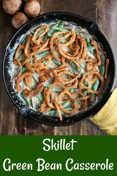 a skillet filled with green bean casserole on top of a wooden table