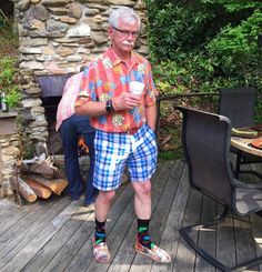 an older man standing on a deck holding a cup