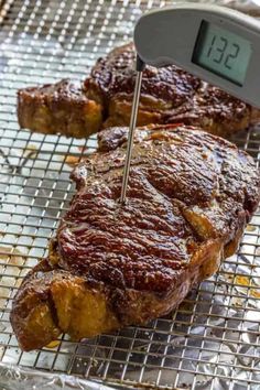 steak being cooked on a grill with an electronic thermometer in front of it