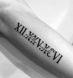 a black and white photo of a roman numeral tattoo on the left inner arm