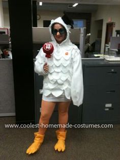 a woman dressed as a chicken holding a lollipop in an office cubicle