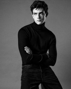 black and white photograph of a man in a turtle neck sweater with his arms crossed