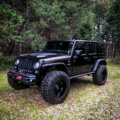 a black jeep parked in front of some trees