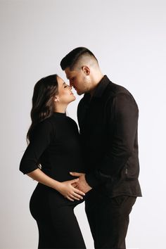 a man and woman kissing each other while standing next to each other in front of a white background