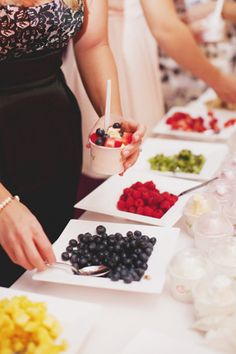 people are serving themselves food on plates at a table with drinks and candy bar signs