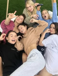 a group of young women sitting on top of a grass covered field next to each other