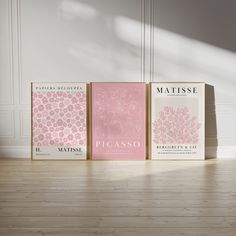 three books sitting on top of a hard wood floor next to each other in front of a white wall