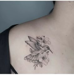 a woman's chest with a hummingbird and flowers tattoo on her left side