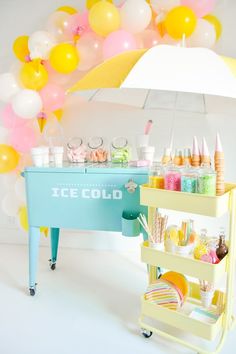 an ice cream stand with balloons and confetti on the table in front of it