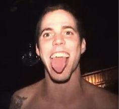 a shirtless man with his tongue out in front of the camera, making a funny face