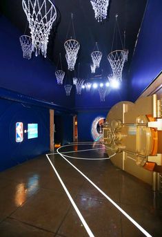 an indoor basketball court with several lights hanging from the ceiling and hoops on the wall