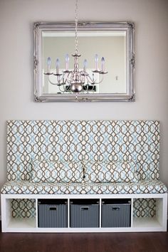 a white bench sitting under a mirror next to a chandelier