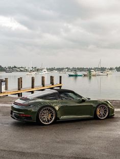 a green sports car parked in front of a body of water