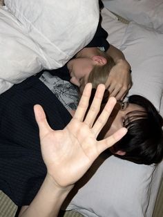 two people laying on a bed with their hands in the air