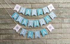 a happy birthday banner with snowflakes and paper streamers on a brick wall