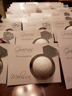 a table topped with lots of white cards and silver place settings on top of each other