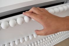 a person's hand on top of an abacust with white balls attached to it