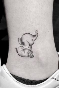 a small elephant tattoo on the side of a woman's ankle, with an elephant sitting on top of it