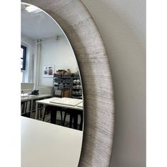 an oval mirror hanging on the side of a wall next to a table and chairs