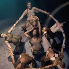 a group of people standing on top of each other in front of a stage light