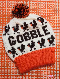 an orange and white knitted hat with the word gobble on it sitting on top of a table