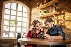 a man and woman sitting at a table with a camera