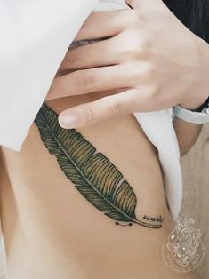 a woman's stomach with a feather tattoo on it