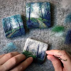 someone is making miniature paintings out of felt and yarns on the floor with their fingers