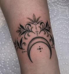 a black and white photo of a tattoo design on the left arm, with a crescent in the middle