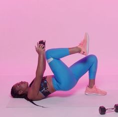 a woman in blue leggings and pink top laying on her stomach with headphones around her neck