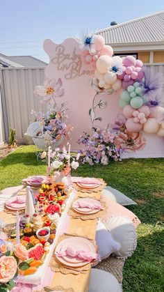 a table set up for a baby shower party with balloons and flowers on the wall