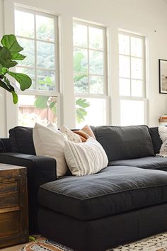 a living room filled with lots of furniture next to two windows and a rug on the floor